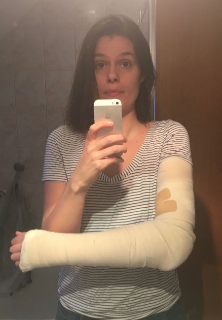 Julia nimmt ein Spiegelselfie auf, auf dem ihr eingegipster rechter Arm zu sehen ist