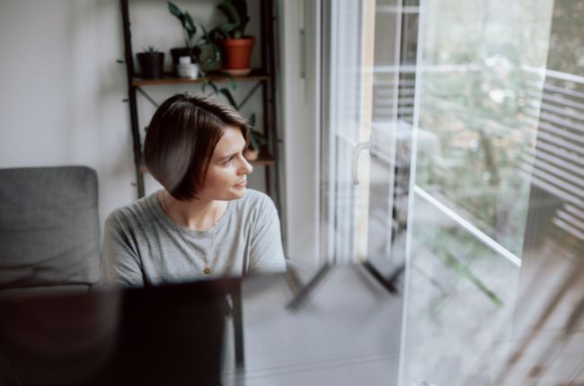 Julia sitzt an ihrem Schreibtisch und blickt nach links aus dem Fenster